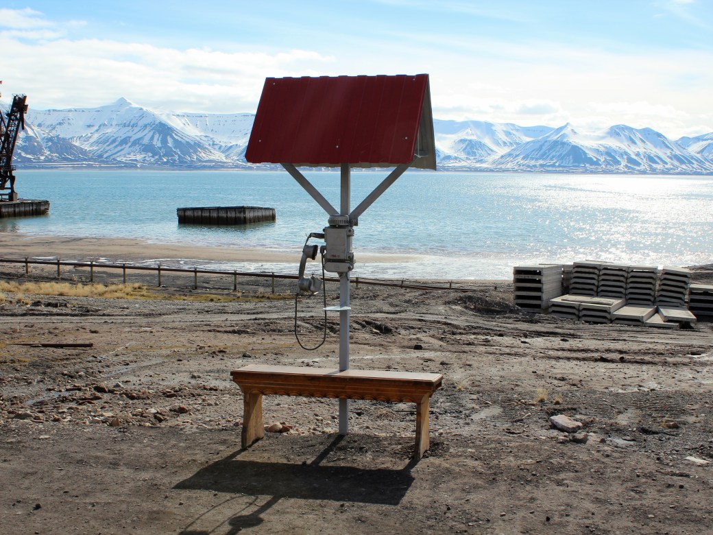 A telephone shelter and bench overlooking the sea and port. Pyramiden, Svalbard
